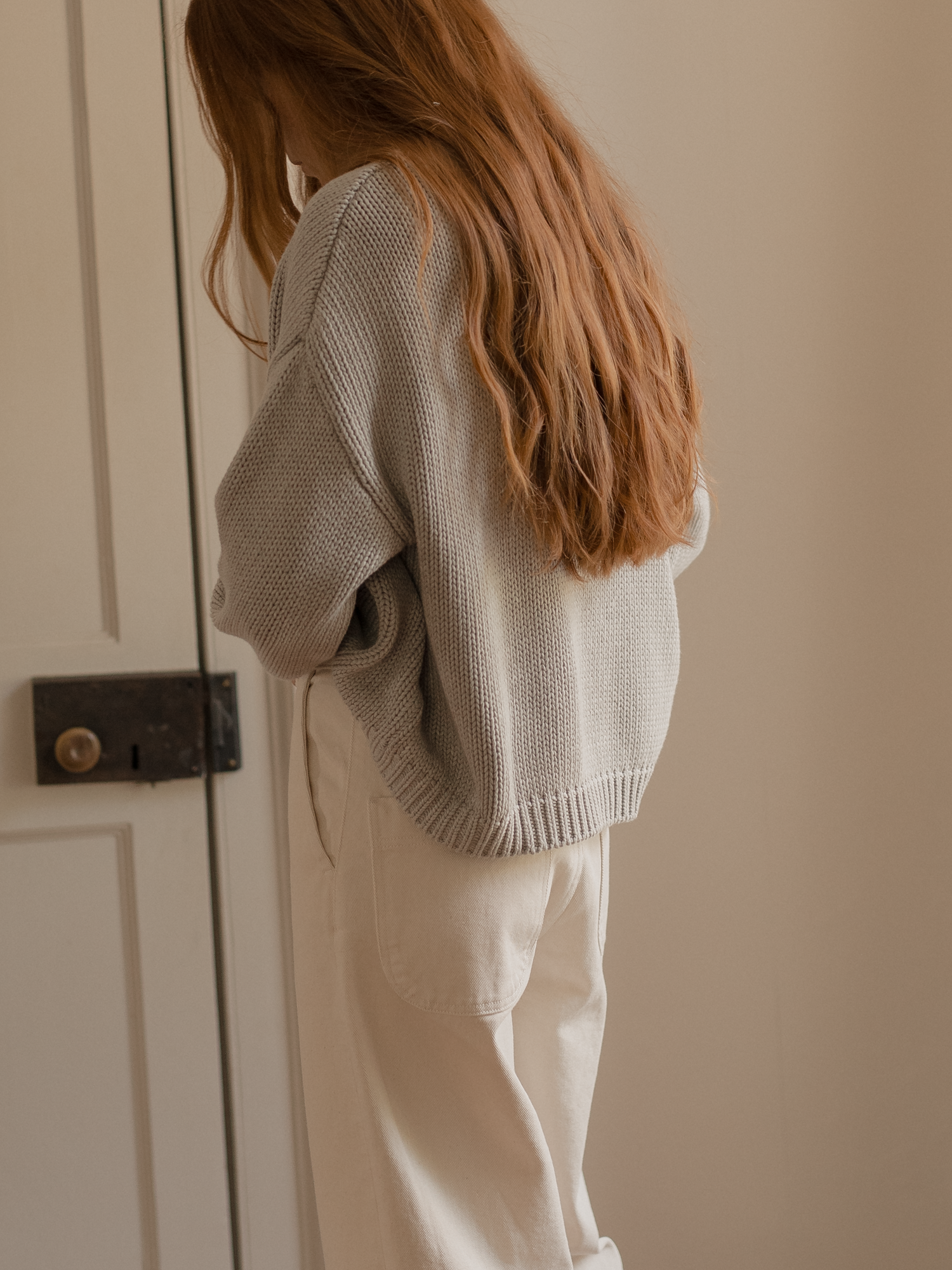 Model wearing the Townes Pullover in Pebble by Gillian Stevens, back view showing chunky knit texture and ribbed hem