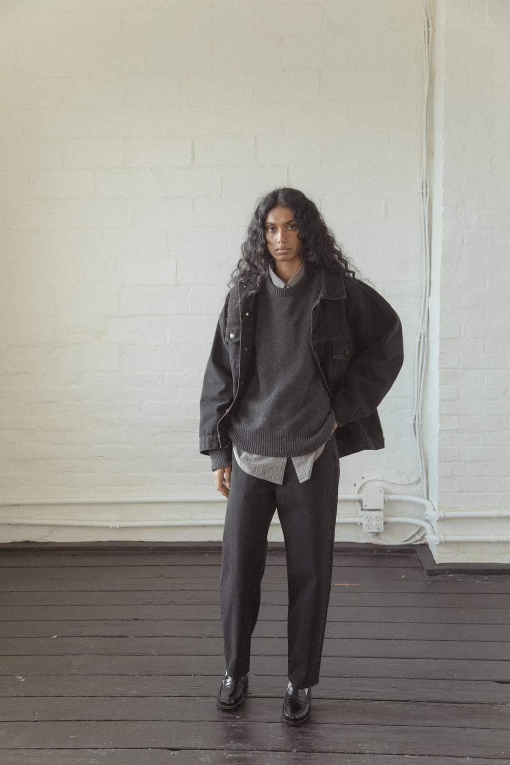 Model wearing the Dara Jean in Noir by Gillian Stevens, full-length front view layered over knit
