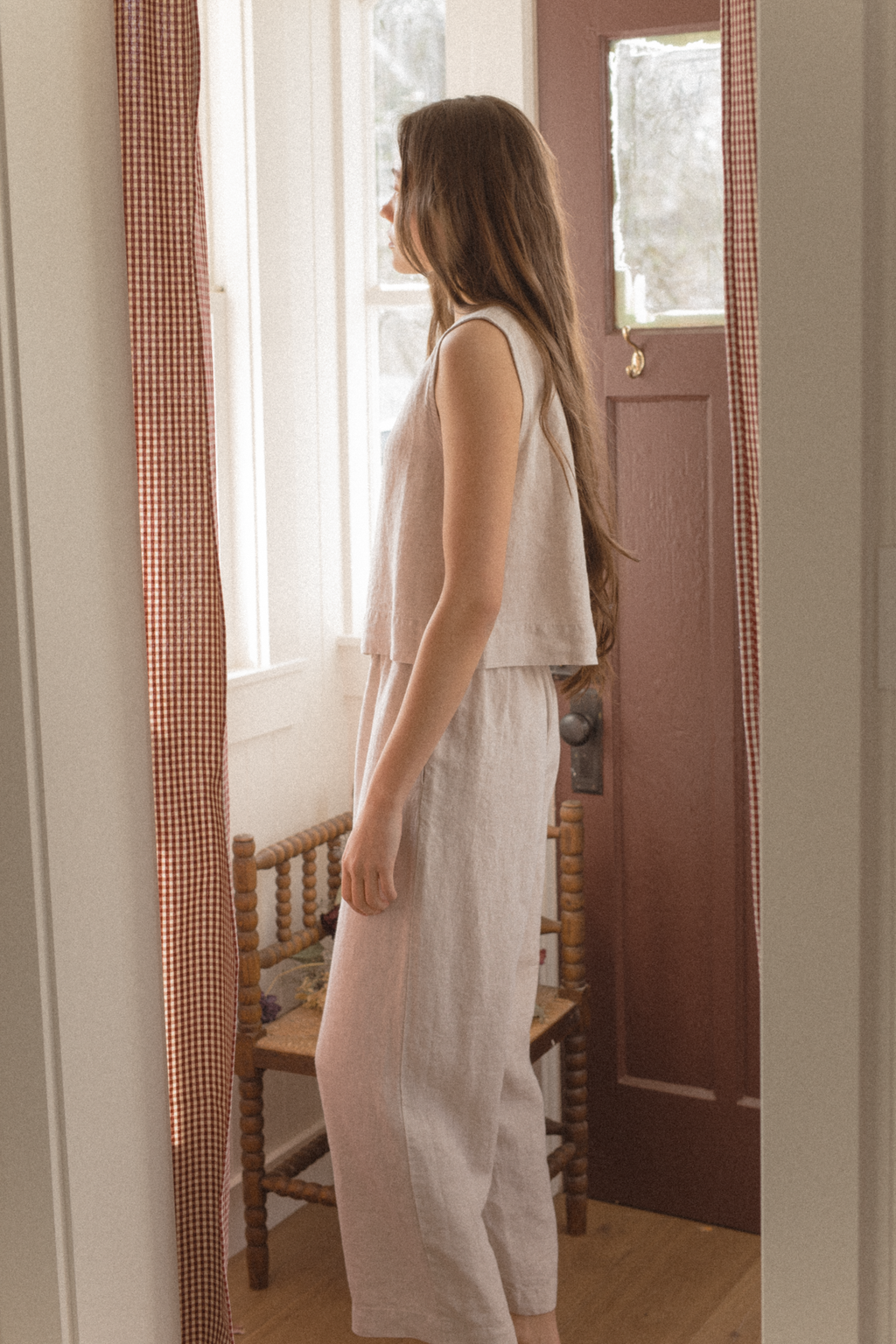 Model wearing the Finley Top in Oatmeal by Gillian Stevens, side profile view in a warm interior setting