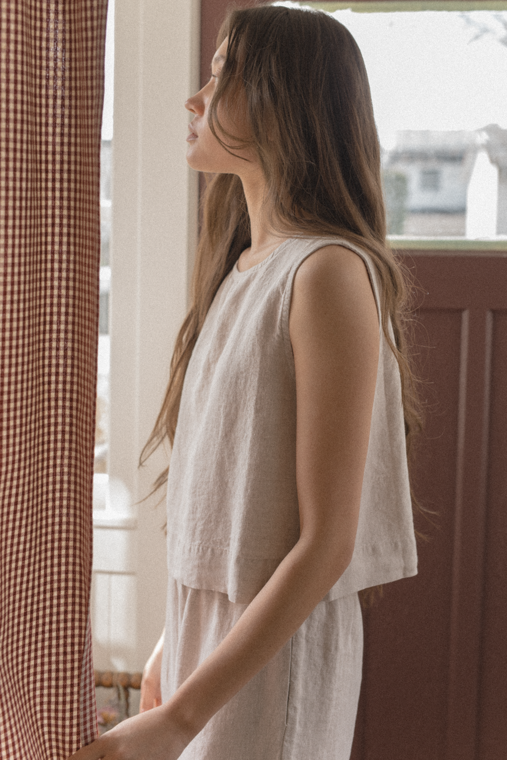Model wearing the Finley Top in Oatmeal by Gillian Stevens, side profile view by window