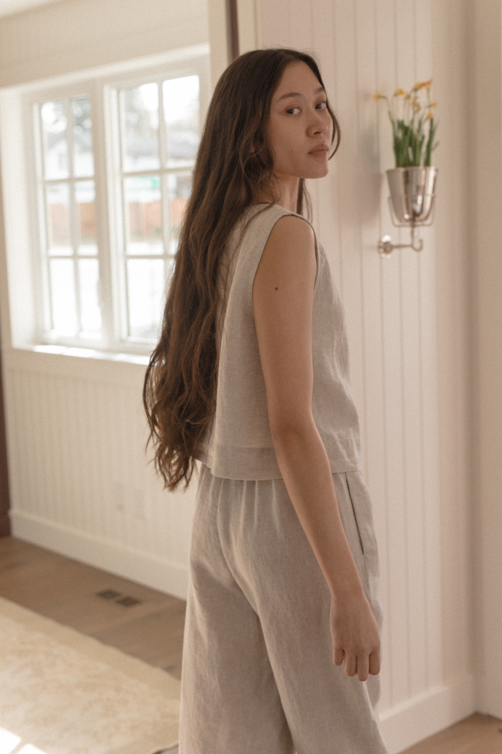 Model wearing the Finley Top in Oatmeal by Gillian Stevens, side-front view in a home setting