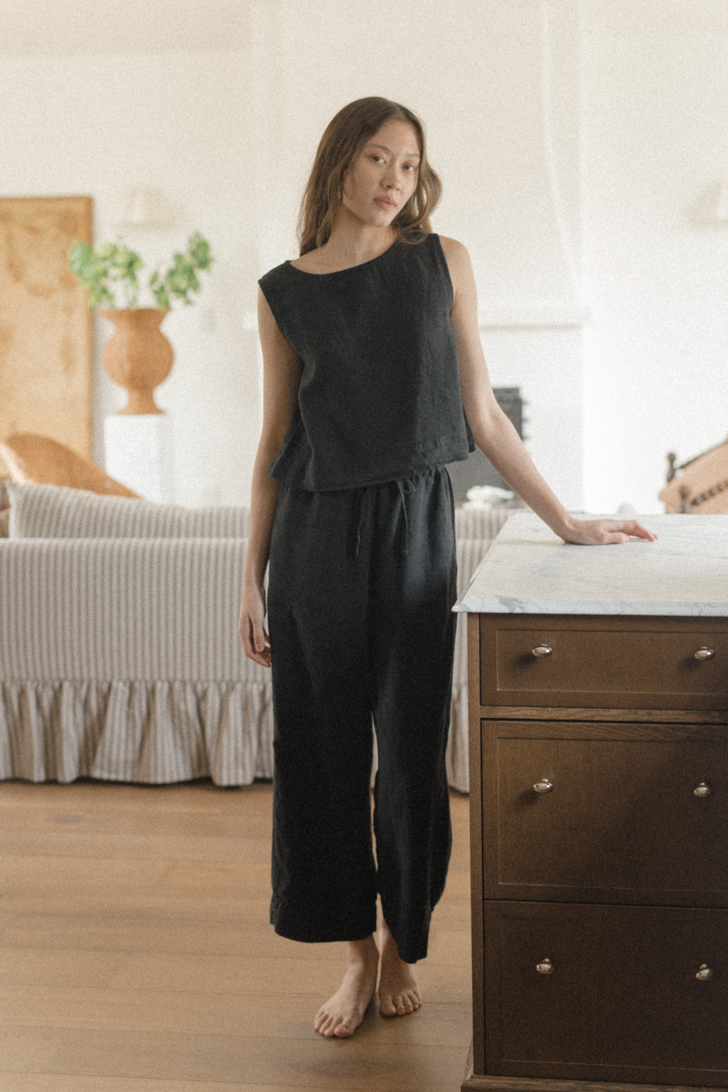 Model wearing the Finley Top in Noir by Gillian Stevens, full-length front view in a home interior setting