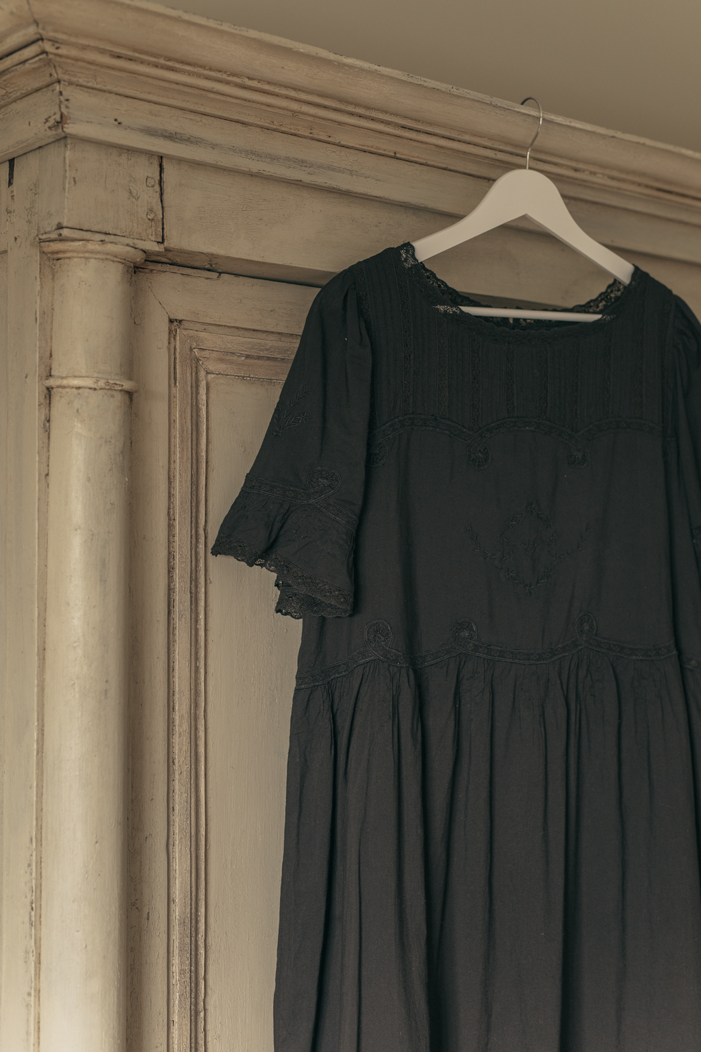The Astrid Dress in Noir by Gillian Stevens, hanged showing lace neckline and sleeve detail