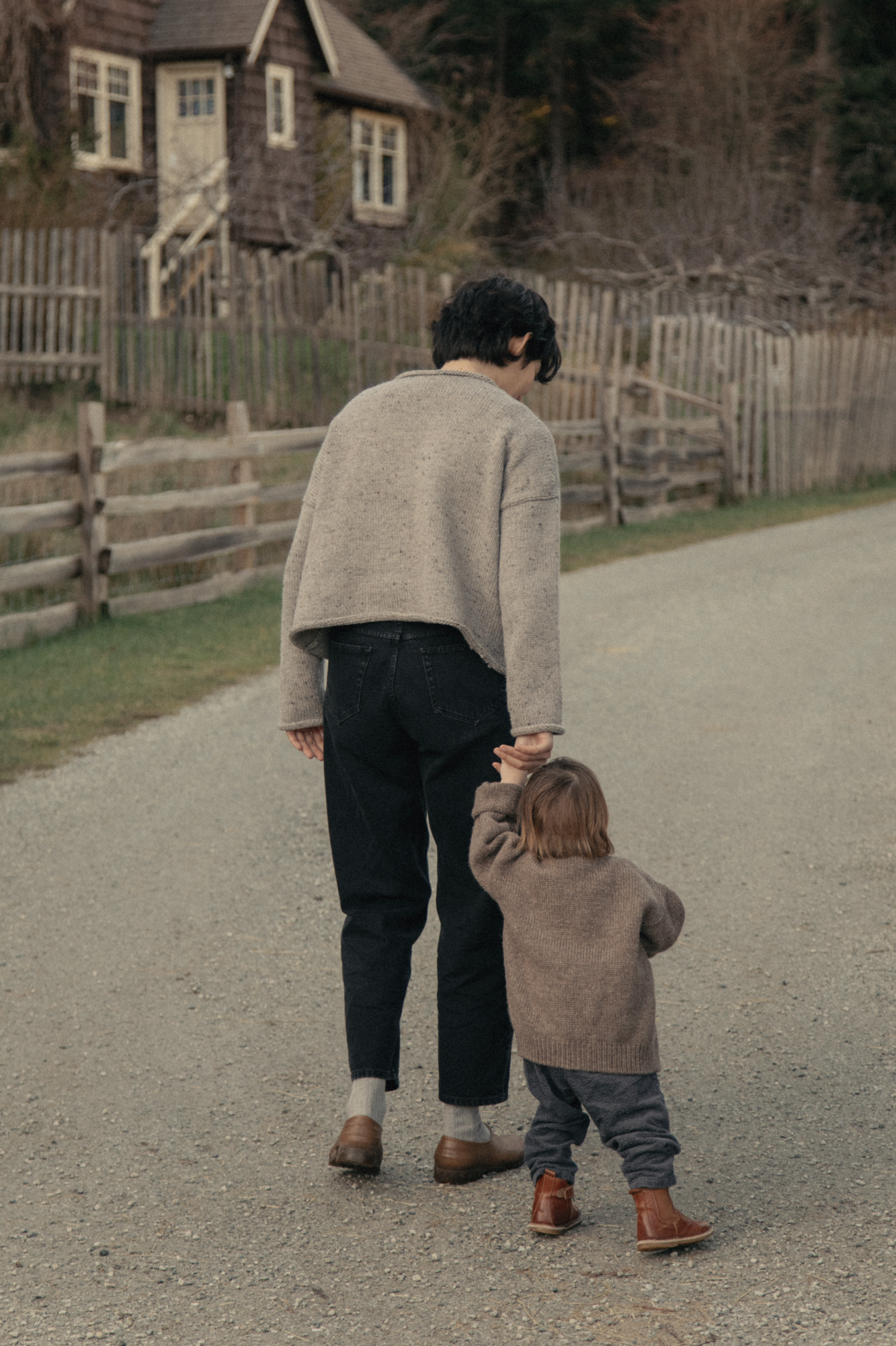 Model wearing the Dara Jean in Noir by Gillian Stevens, back view walking outdoors with child