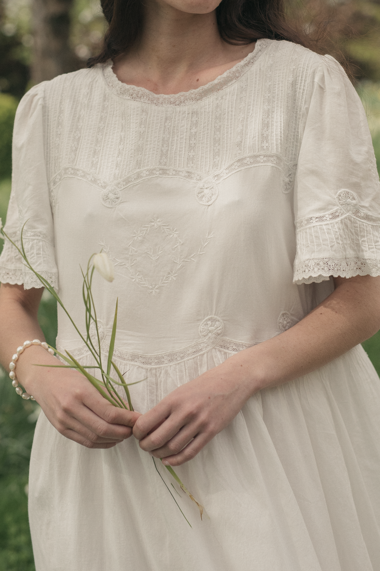 Model wearing the Astrid Dress in Salt by Gillian Stevens, close-up of lace and embroidery bodice detail
