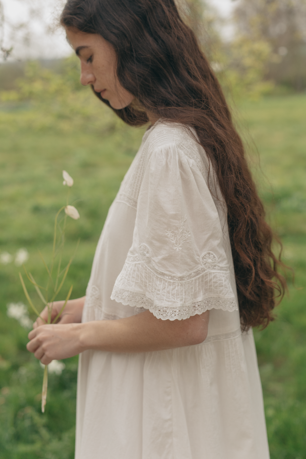 Model wearing the Astrid Dress in Salt by Gillian Stevens, side view showing lace sleeve detail outdoors