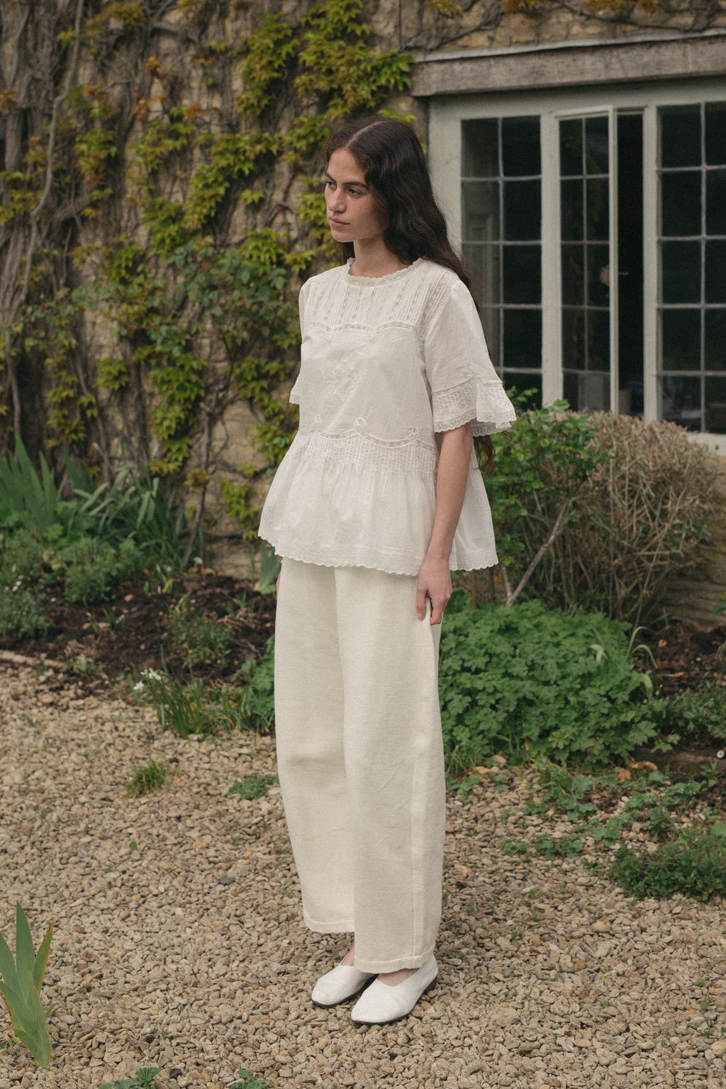 Model wearing the Astrid Blouse in Salt by Gillian Stevens, front view in a garden setting, view 2