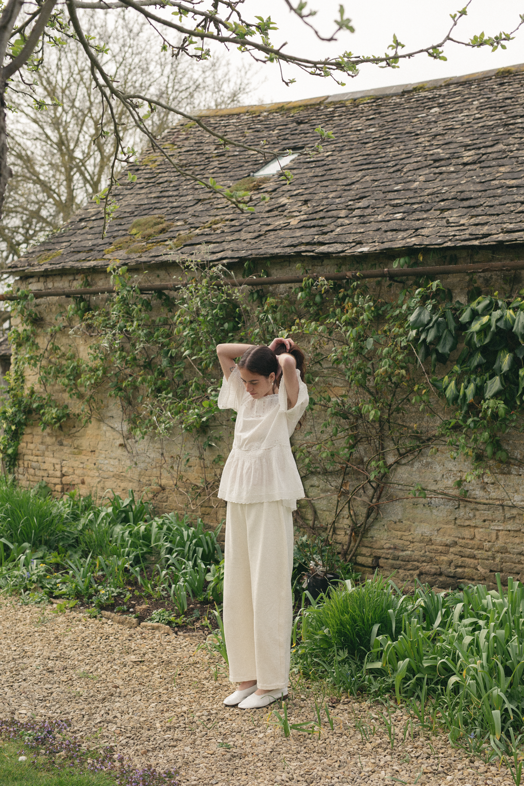 Model wearing the Astrid Blouse in Salt by Gillian Stevens, full-length front view in a garden setting