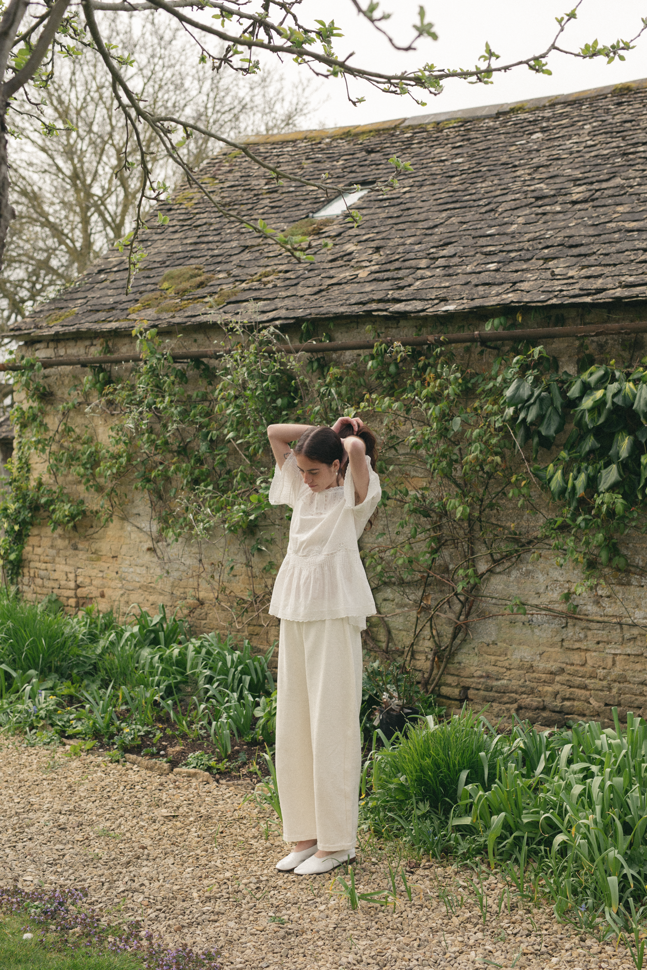 Model wearing the Astrid Blouse in Salt by Gillian Stevens, full-length front view in a garden setting