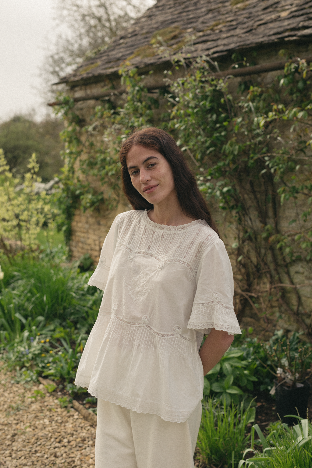 Model wearing the Astrid Blouse in Salt by Gillian Stevens, front view in a garden setting