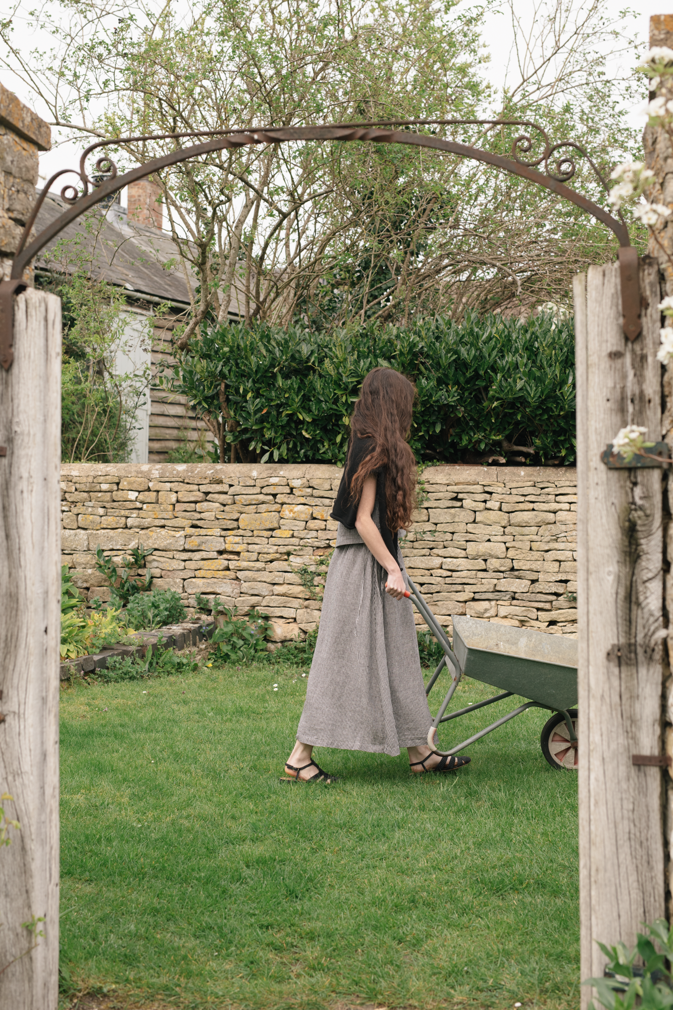 Model wearing the Frances Skirt in Gingham Noir by Gillian Stevens, back view in a garden setting