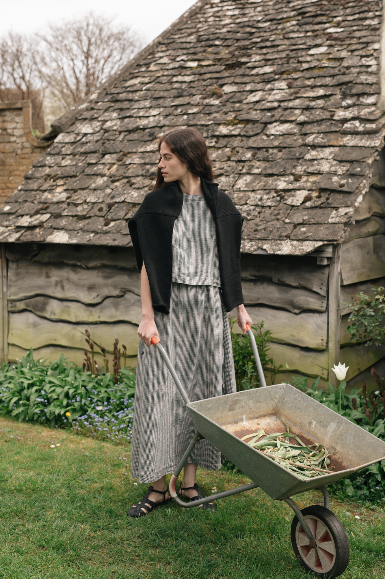 Model wearing the Frances Skirt in Gingham Noir by Gillian Stevens, styled with black knitwear in a garden setting