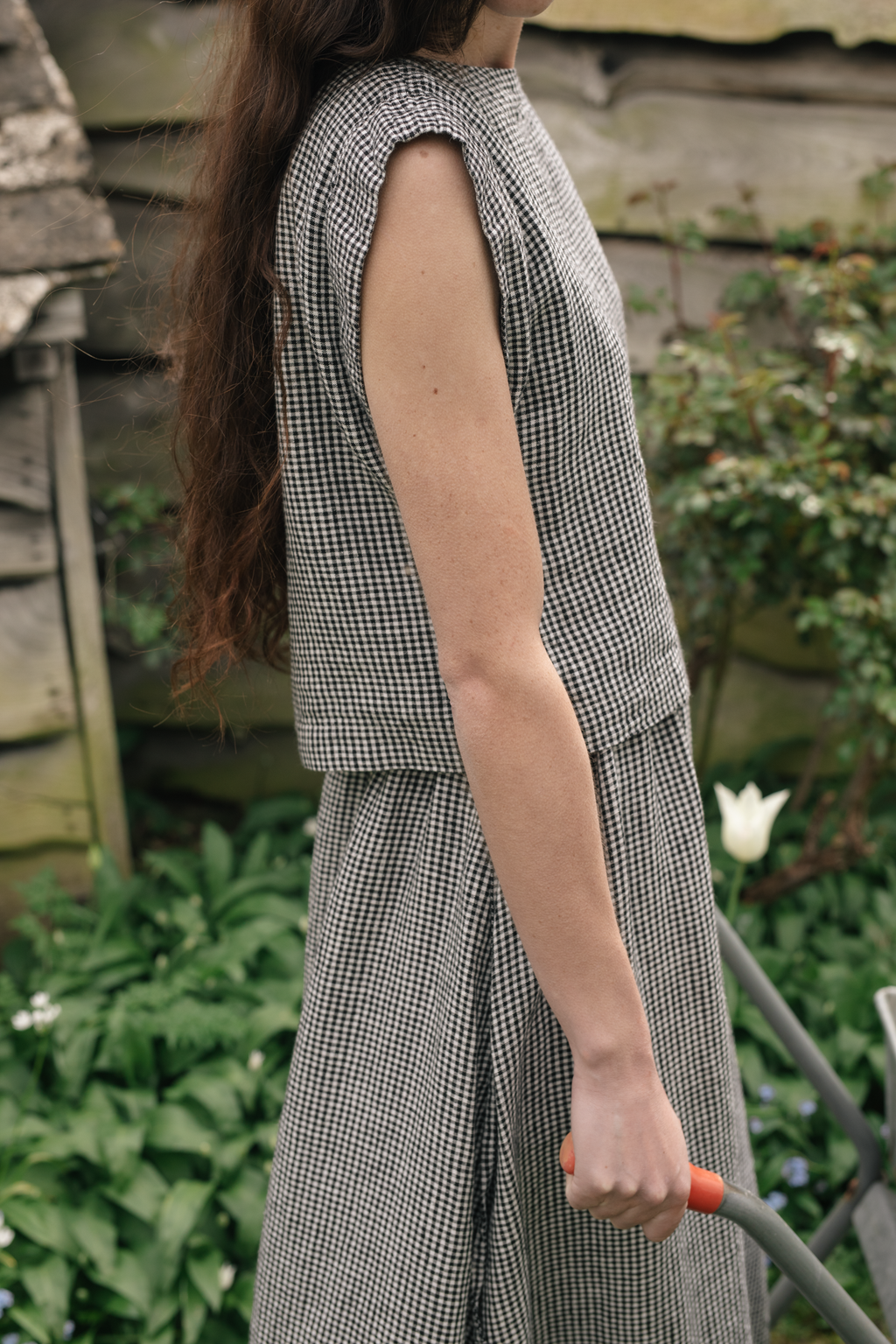 Model wearing the Valley Top in Gingham Noir by Gillian Stevens, side view in a garden setting