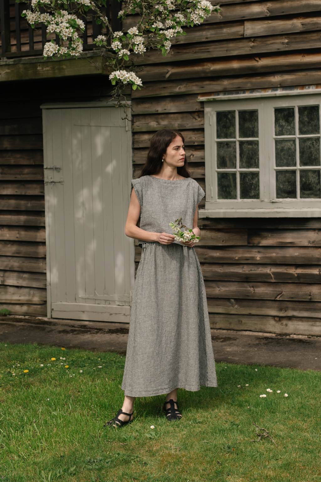 Model wearing the Frances Skirt in Gingham Noir by Gillian Stevens, front view in garden setting, view 2