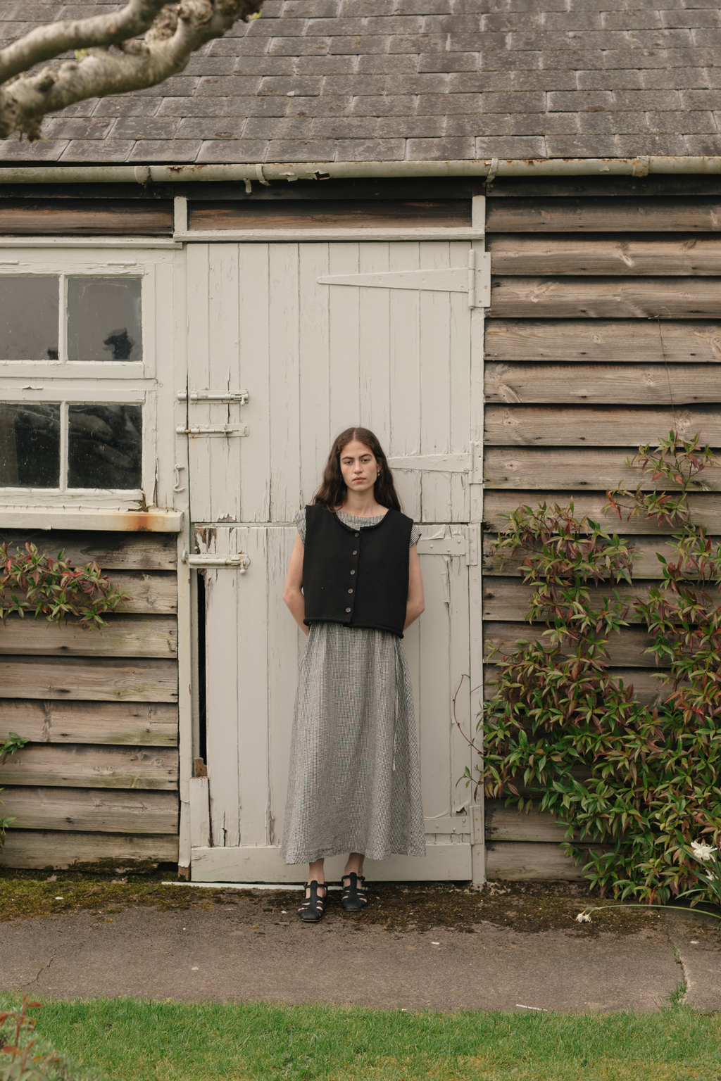 Model wearing the Lennon Vest in Noir by Gillian Stevens, front view outside rustic wooden barn