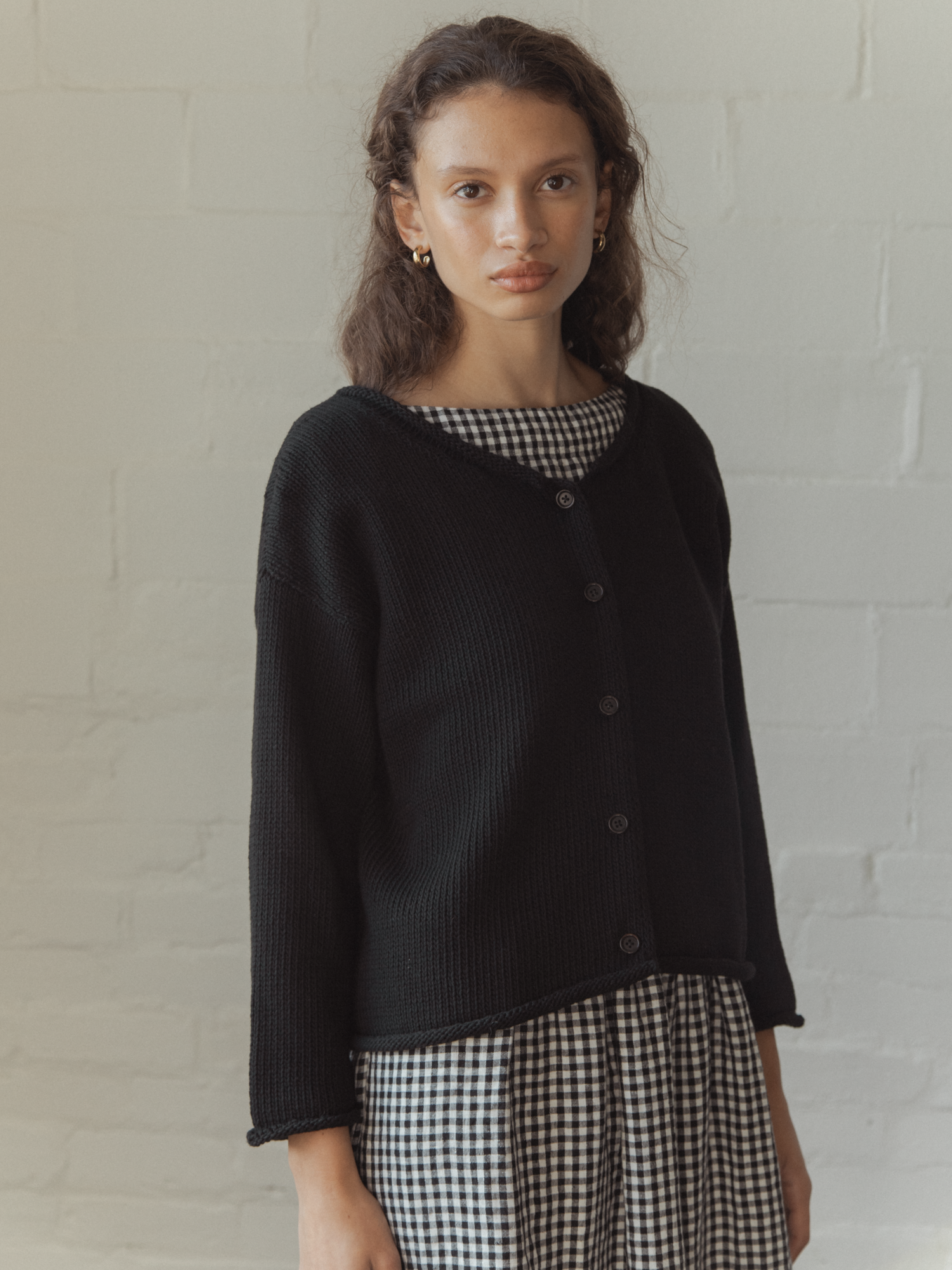 Model wearing the Lennon Cardigan in Noir by Gillian Stevens, three-quarter front view showing button detail