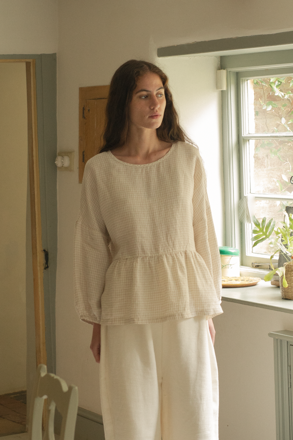 Model wearing the Darla Blouse in Oat Plaid by Gillian Stevens, front view in a light-filled room