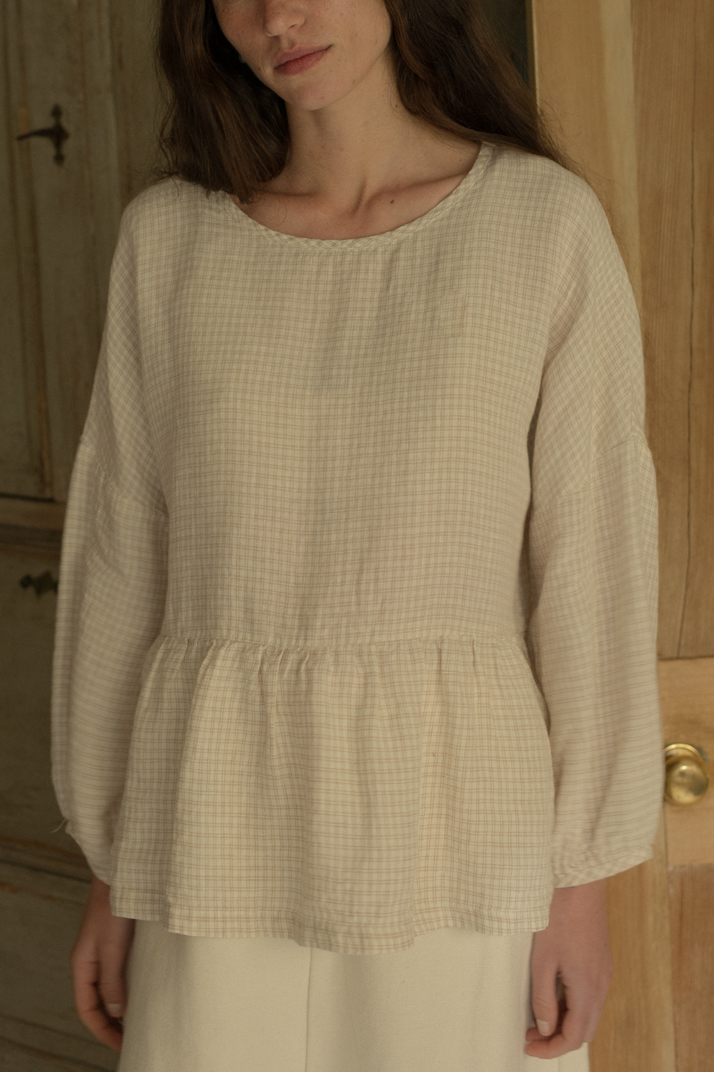 Model wearing the Darla Blouse in Oat Plaid by Gillian Stevens, front view showing gathered peplum hem