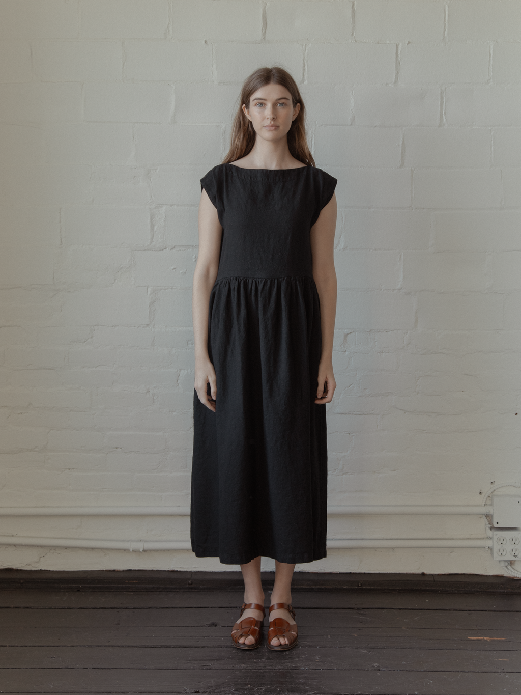 Model wearing the Valley Dress in Noir by Gillian Stevens, front view showing gathered skirt and cap sleeves