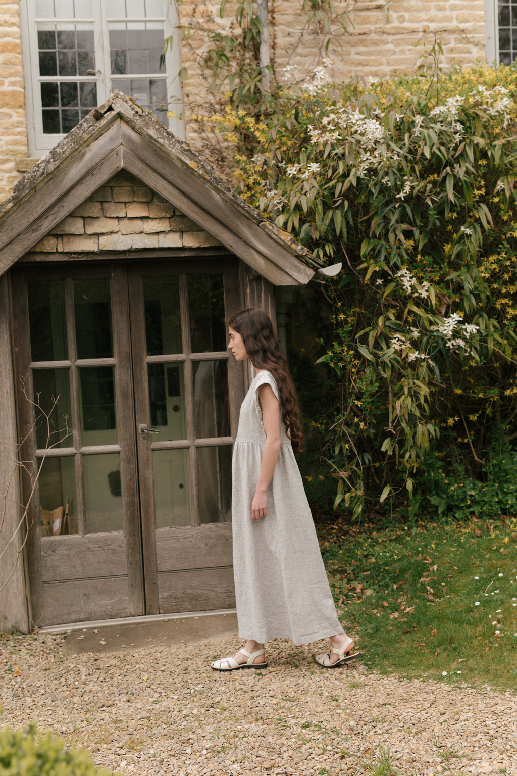 Model wearing the Valley Dress in Charcoal Stripe by Gillian Stevens, side view in garden setting