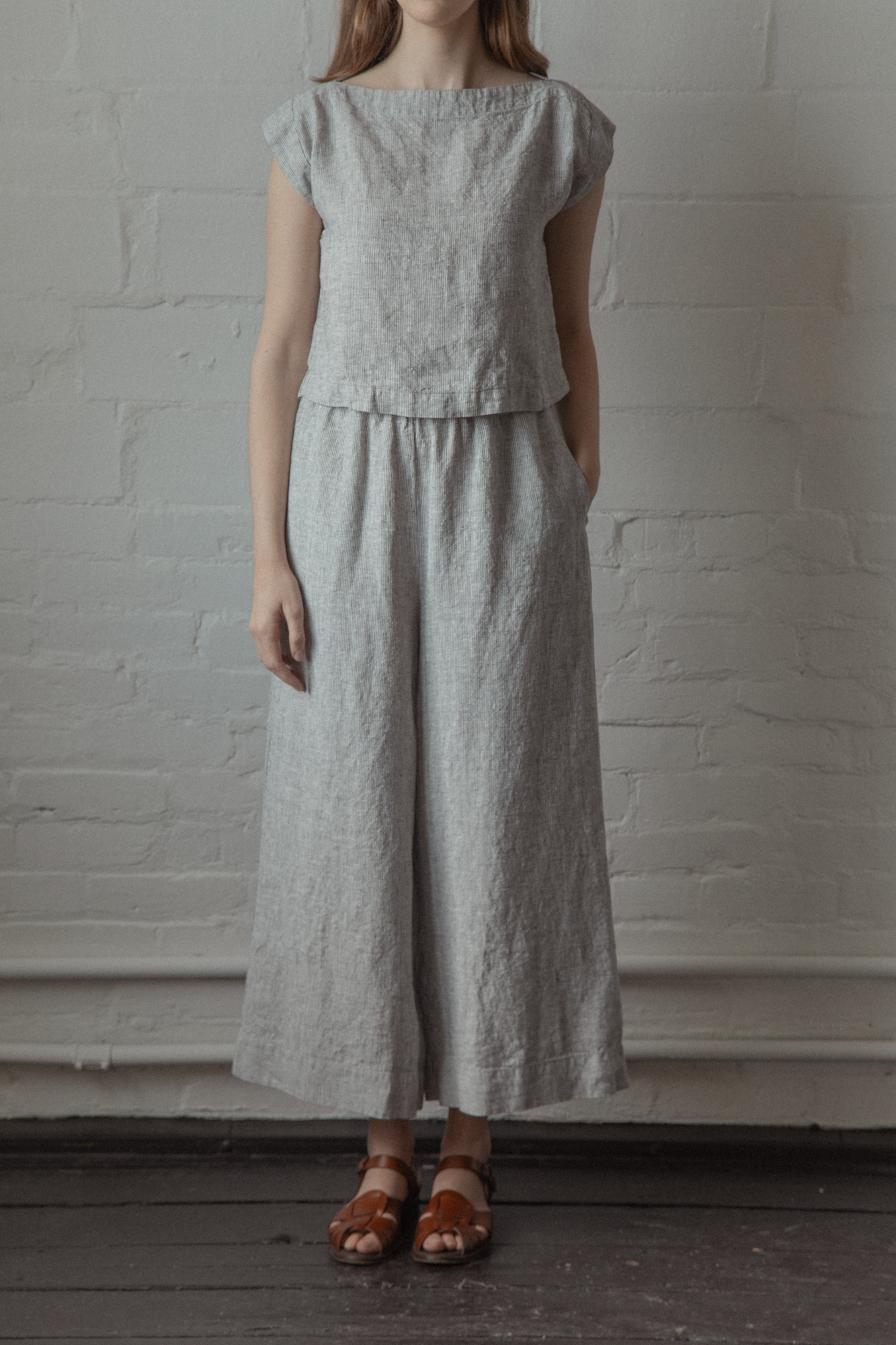 Model wearing the Valley Top in Charcoal Stripe by Gillian Stevens, front view styled with wide-leg linen trousers