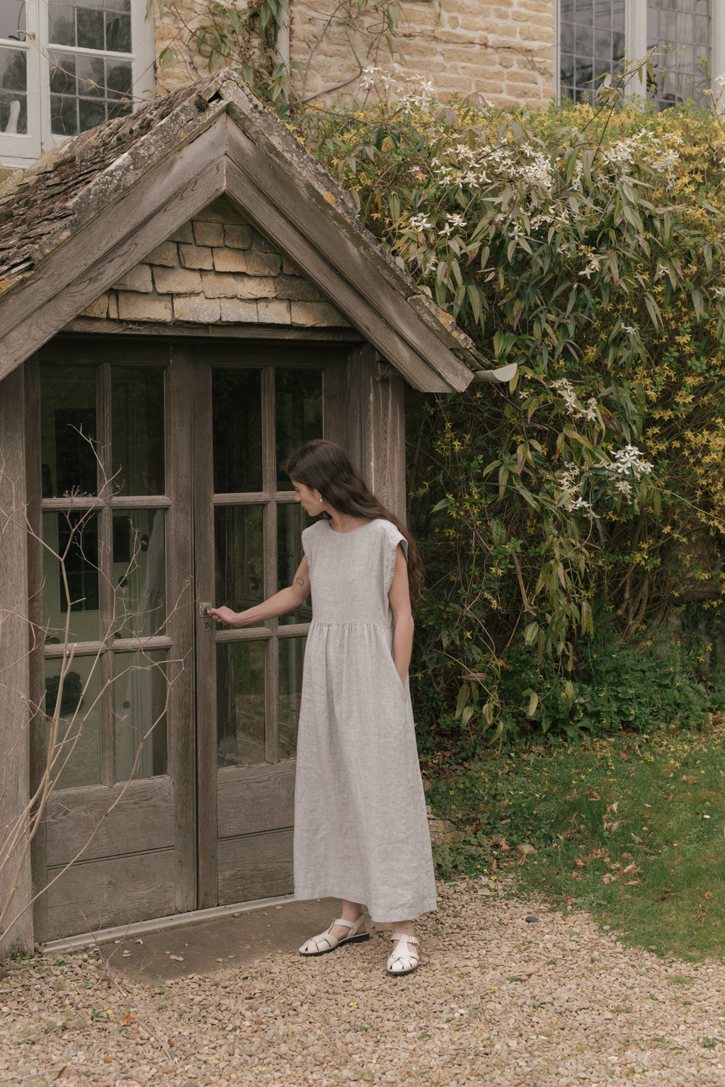 Model wearing the Valley Dress in Charcoal Stripe by Gillian Stevens, side view in garden setting, view 4