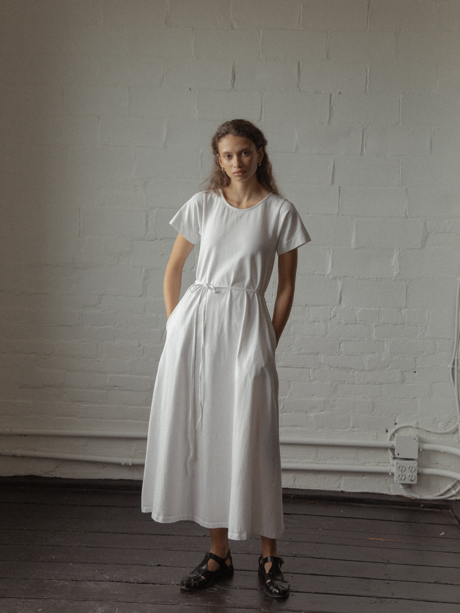 Model wearing the Palmer Dress in Salt by Gillian Stevens, front view showing tie waist and full midi skirt