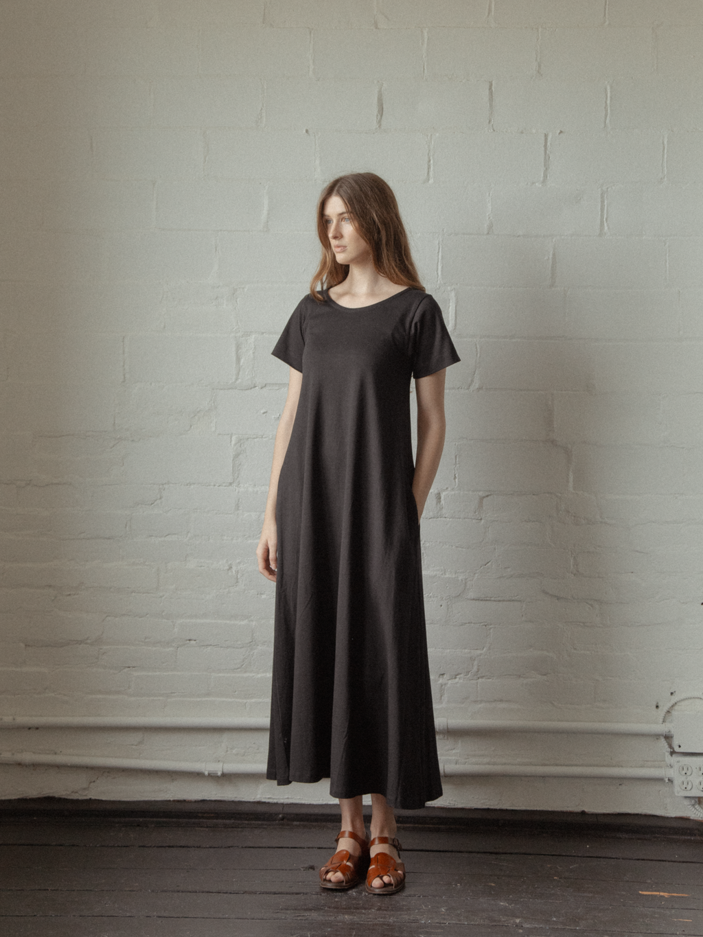 Model wearing the Palmer Dress in Noir by Gillian Stevens, front view showing flared maxi length and short sleeves