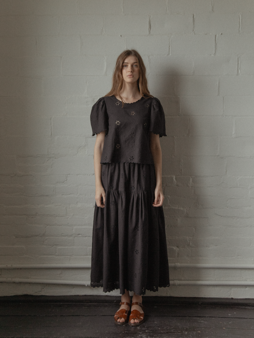 Model wearing the Stella Skirt in Noir by Gillian Stevens, styled with matching broderie top, front view