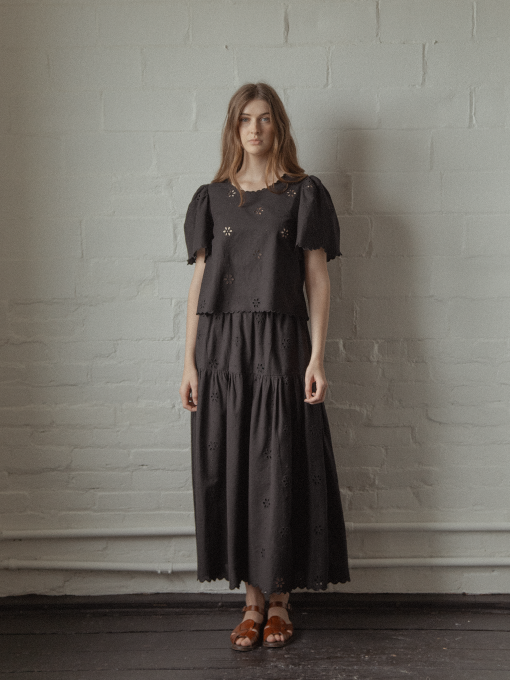 Model wearing the Stella Skirt in Noir by Gillian Stevens, styled with matching broderie top, front view