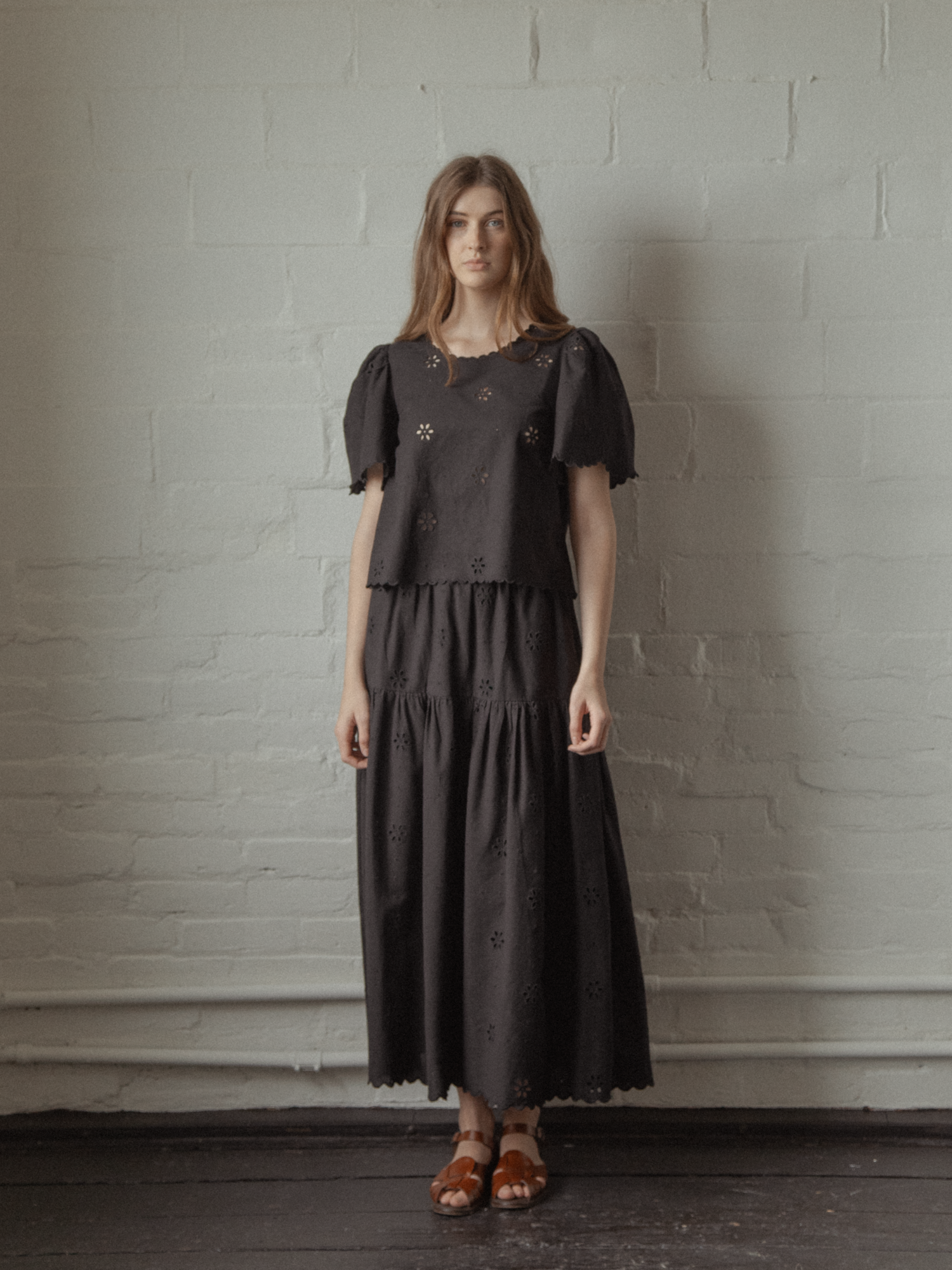Model wearing the Stella Skirt in Noir by Gillian Stevens, styled with matching broderie top, front view