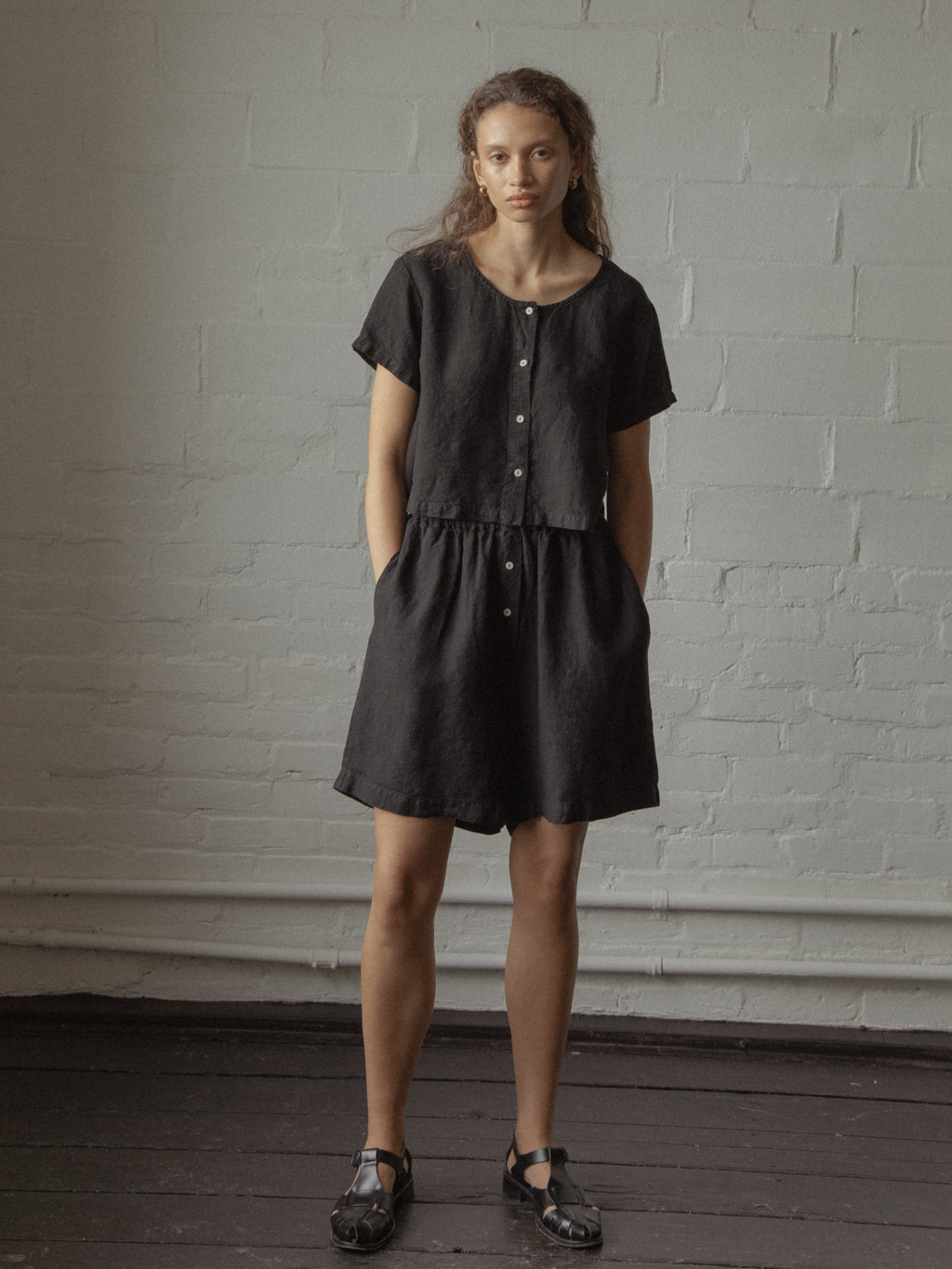 Model wearing the Sally Shorts in Noir by Gillian Stevens, front view styled with matching black linen top