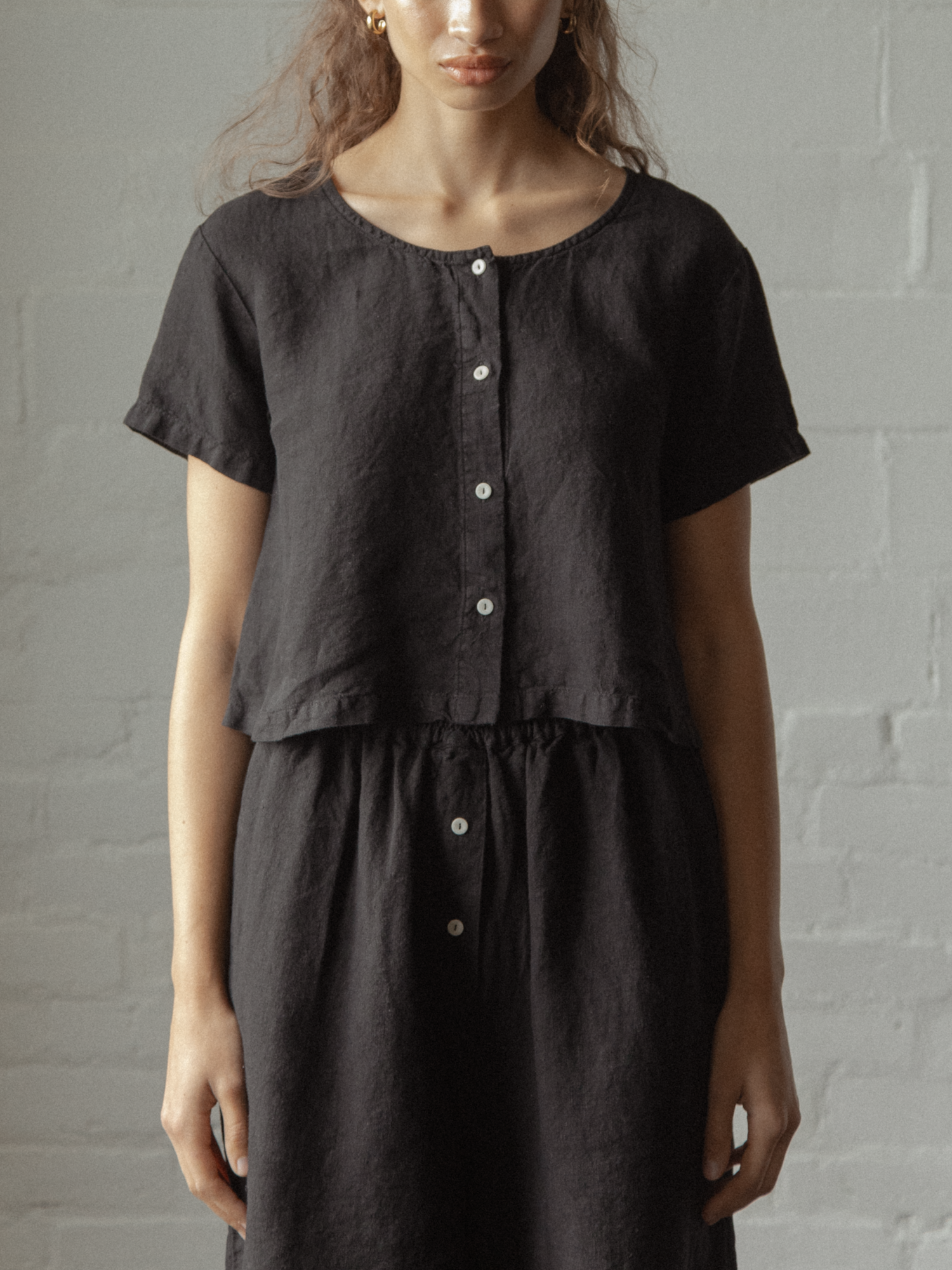 Model wearing the Wren Top in Noir by Gillian Stevens, front view showing button placket and cropped linen silhouette