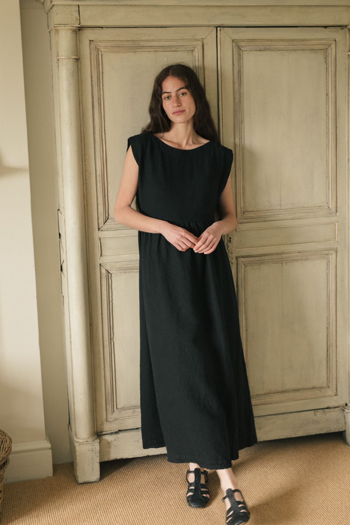 Model wearing the Valley Dress in Noir by Gillian Stevens, full-length front view in a styled interior setting