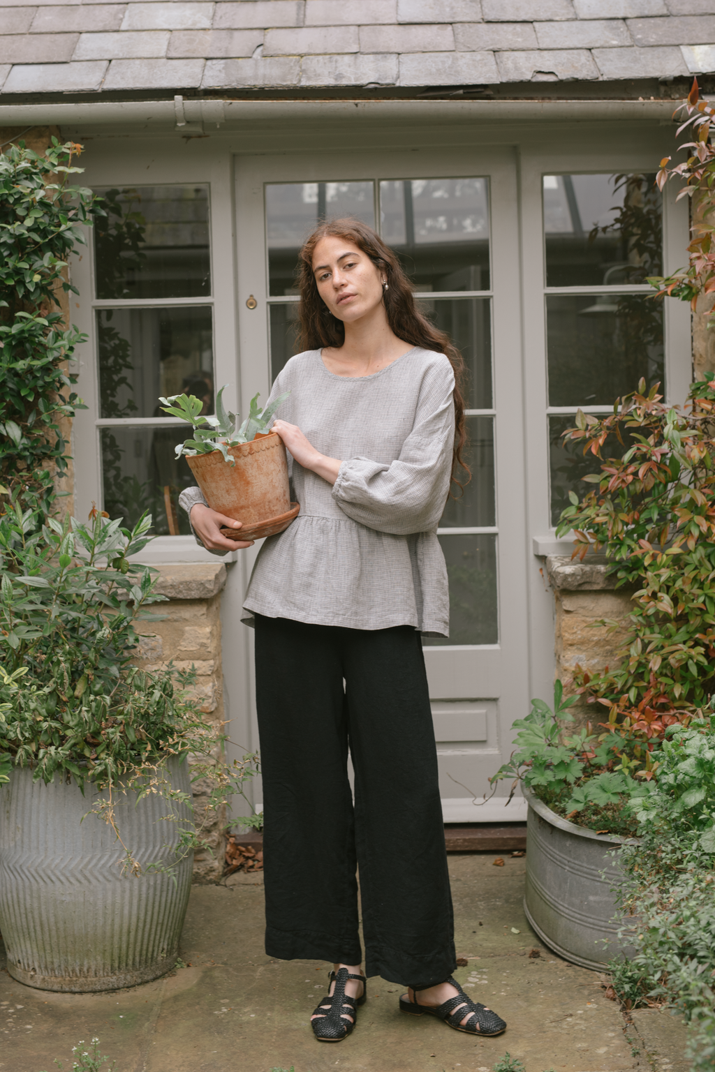 Model wearing the Darla Blouse in Dove Check by Gillian Stevens, full-length front view in garden setting