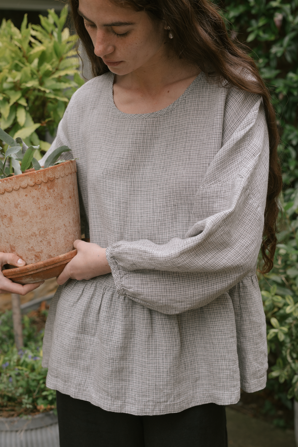 Model wearing the Darla Blouse in Dove Check by Gillian Stevens, front view in a garden setting