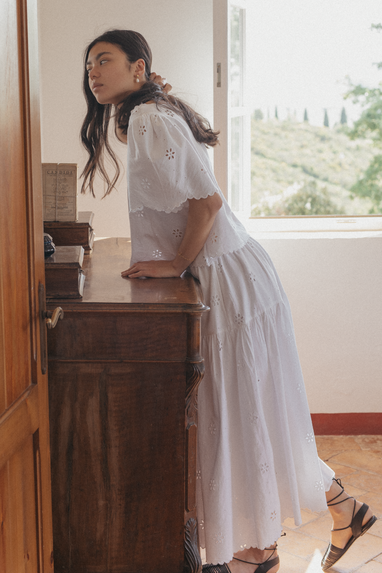Model wearing the Stella Skirt in Salt by Gillian Stevens, side view leaning against a wooden dresser
