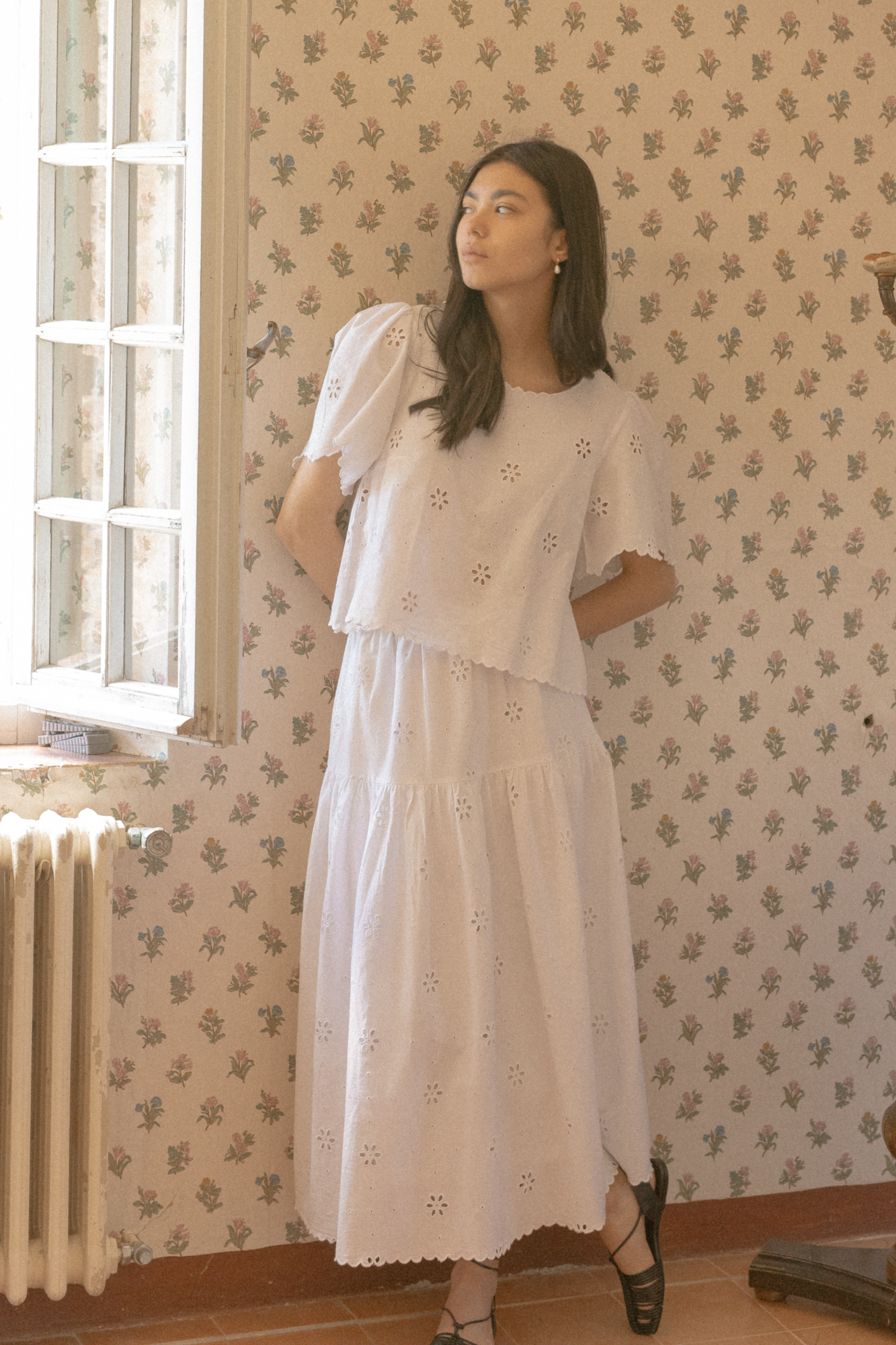 Model wearing the Stella Top in Salt by Gillian Stevens, styled with a white eyelet skirt, front three-quarter view