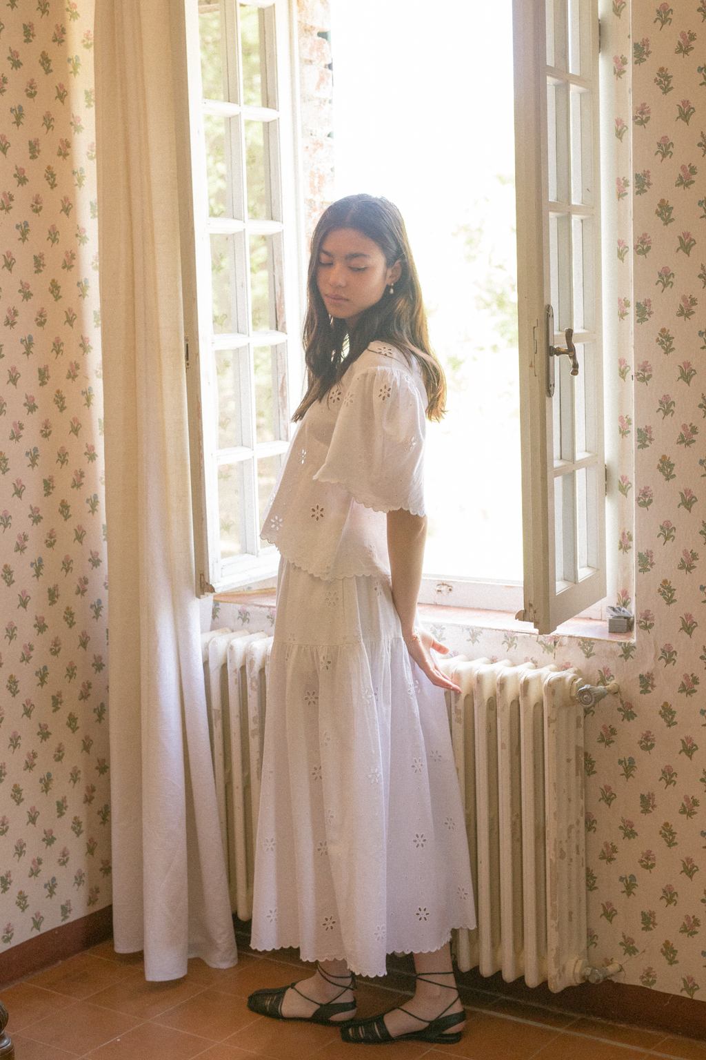 Model wearing the Stella Top in Salt by Gillian Stevens, side view by an open French window