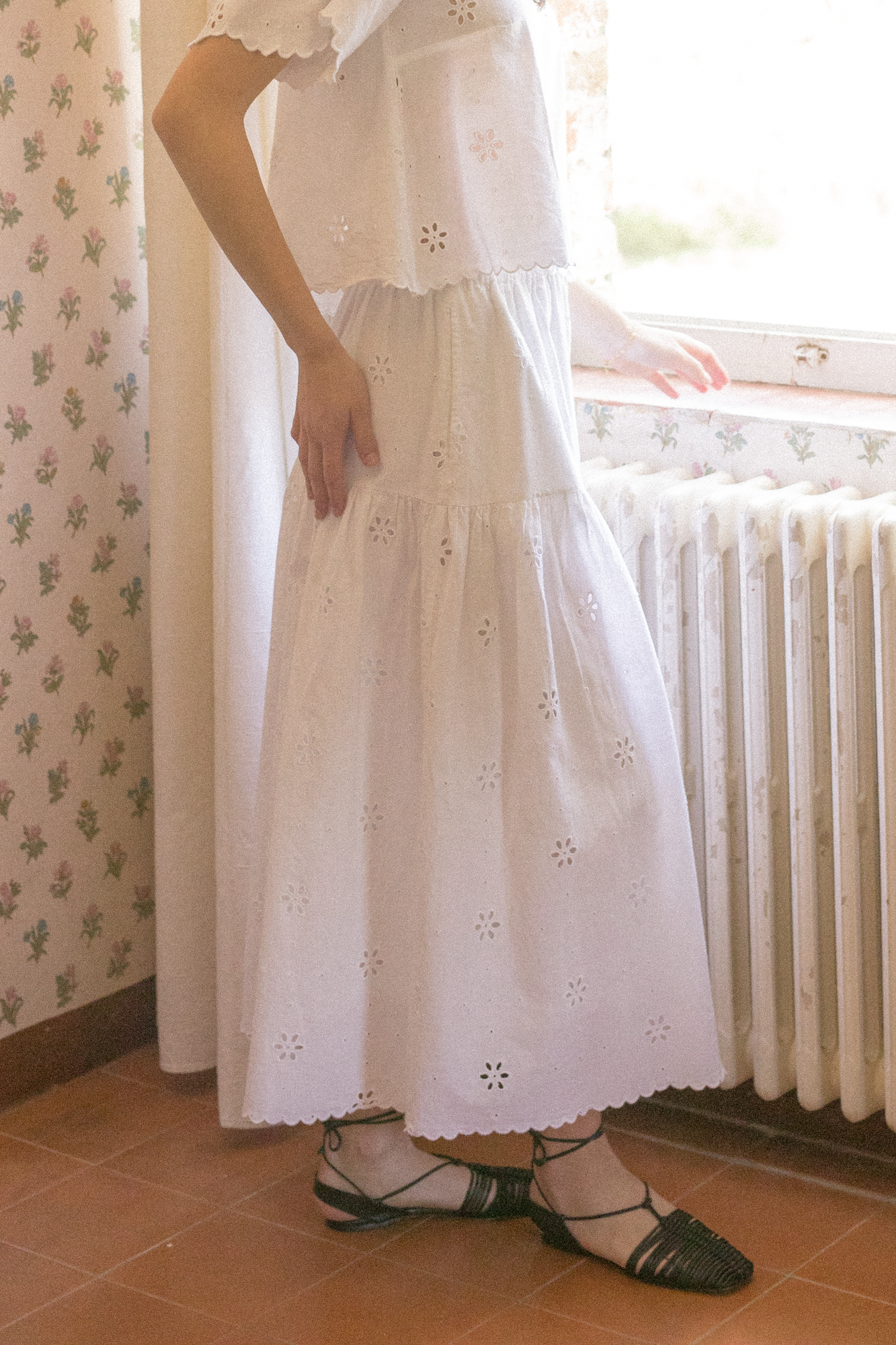 Model wearing the Stella Skirt in Salt by Gillian Stevens, side view showing tiered eyelet detail and scalloped hem