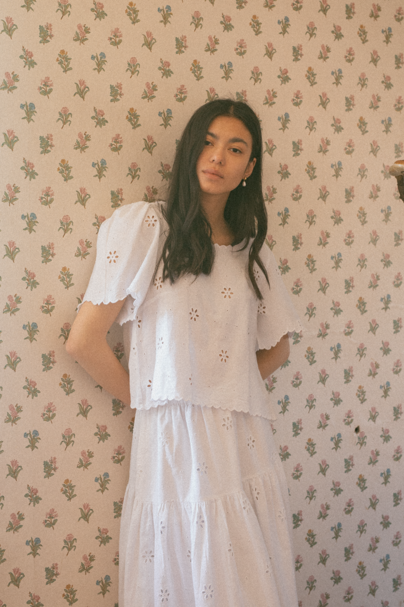Model wearing the Stella Top in Salt by Gillian Stevens, front view against floral wallpaper