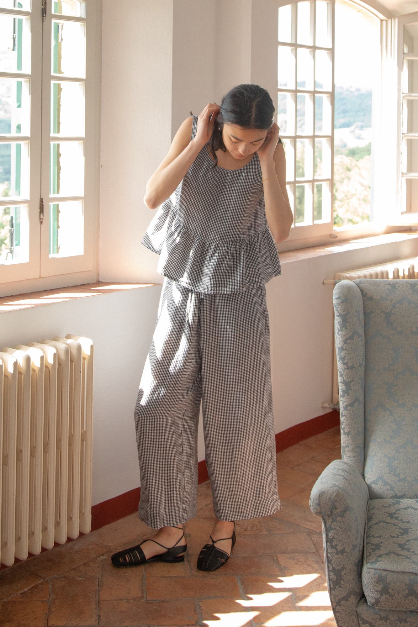 Model wearing the Olive Pant in Marine Gingham by Gillian Stevens, full-length front view in a sunlit room