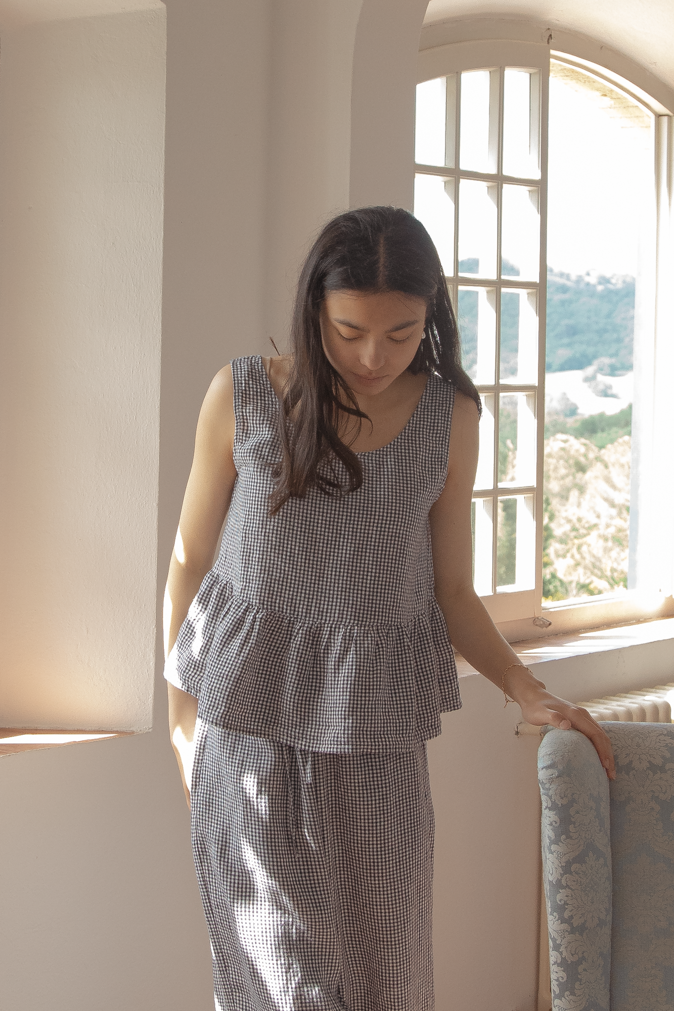 Model wearing the Marlowe Top in Marine Gingham by Gillian Stevens, front view beside a sunlit arched window