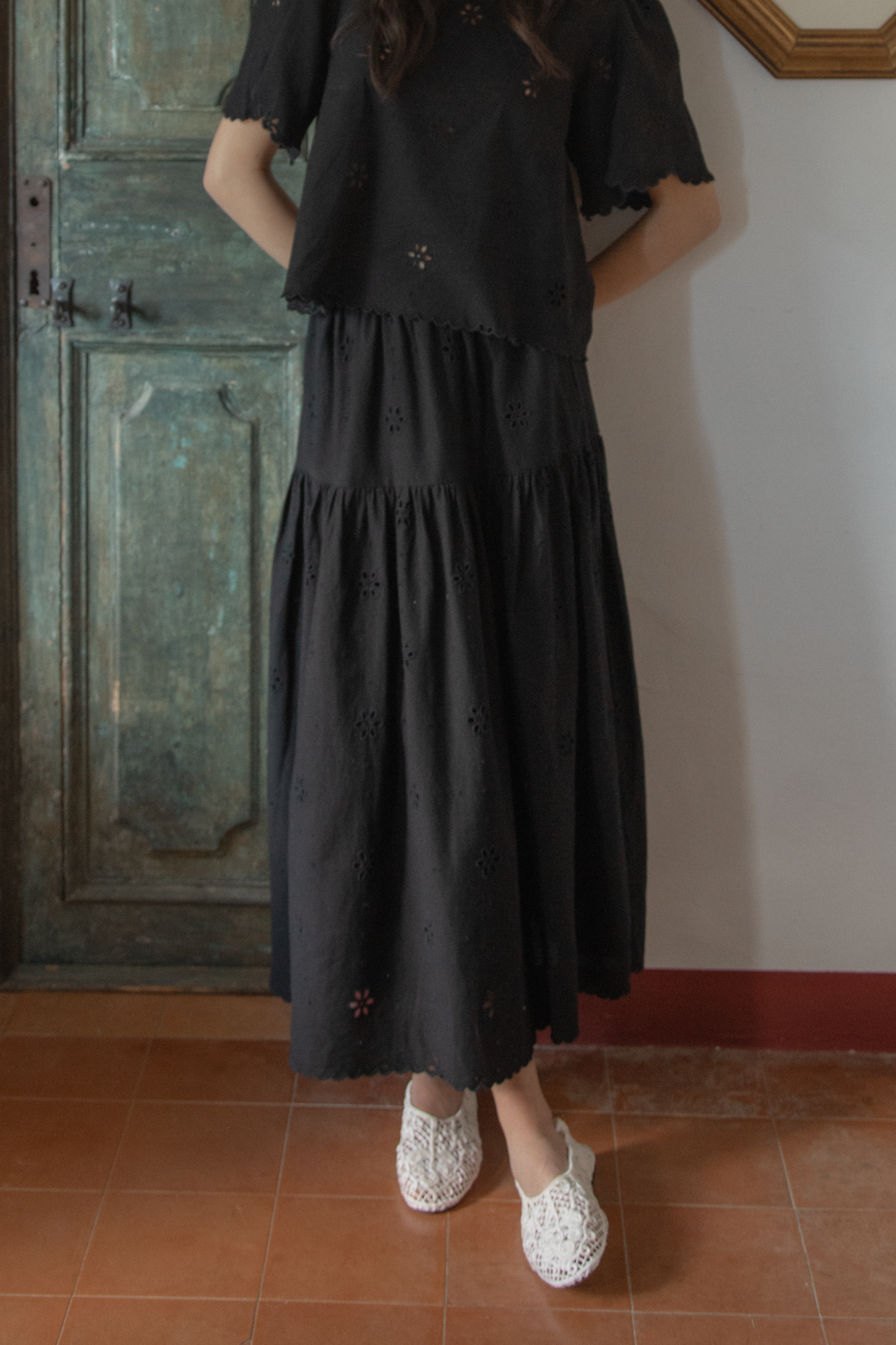 Model wearing the Stella Skirt in Noir by Gillian Stevens, front view showing tiered eyelet hem detail