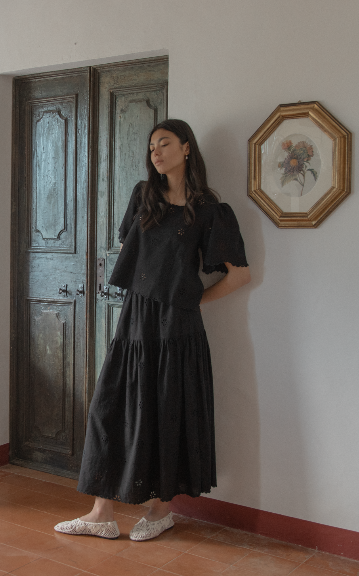 Model wearing the Stella Skirt in Noir by Gillian Stevens, front view showing tiered maxi length and eyelet detail