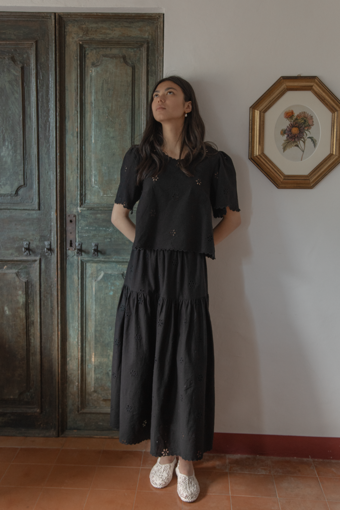 Model wearing the Stella Skirt in Noir by Gillian Stevens, full-length front view styled with matching broderie top