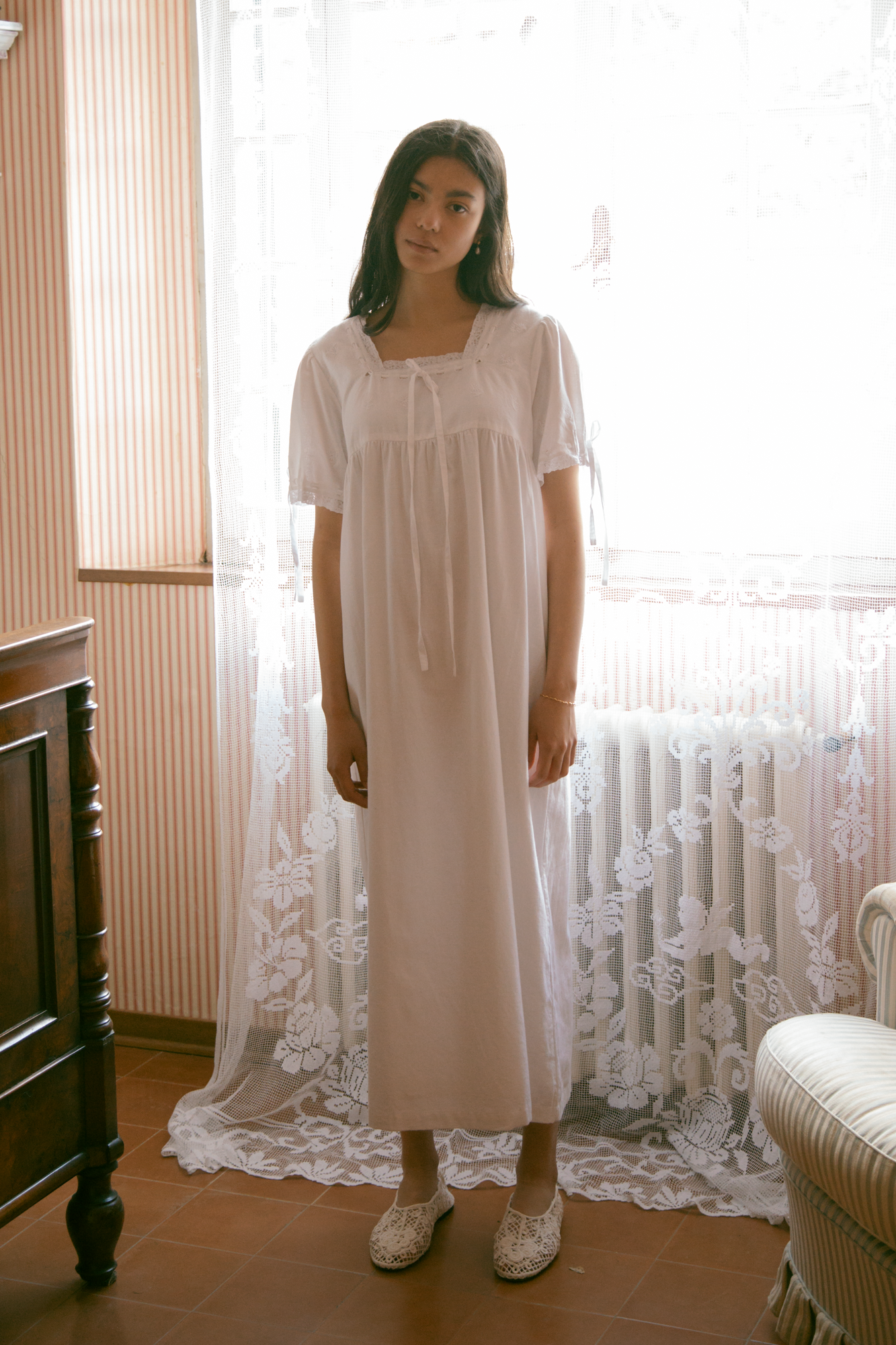 Model wearing the Dace Dress in Salt by Gillian Stevens, full-length front view in a vintage-styled room