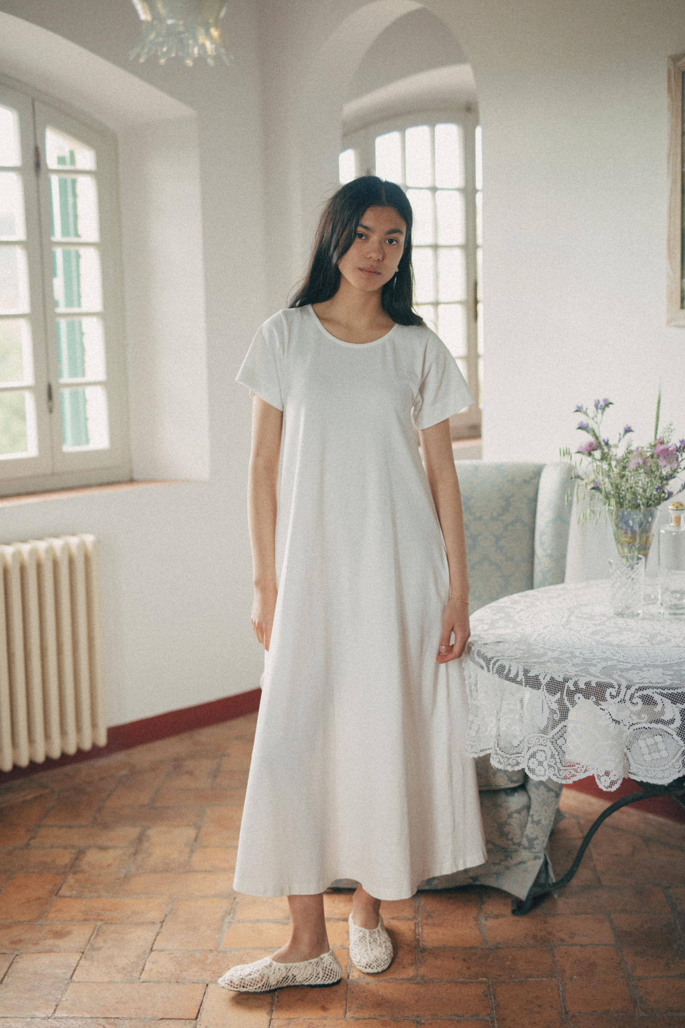 Model wearing the Palmer Dress in Salt by Gillian Stevens, front view in a sunlit European interior
