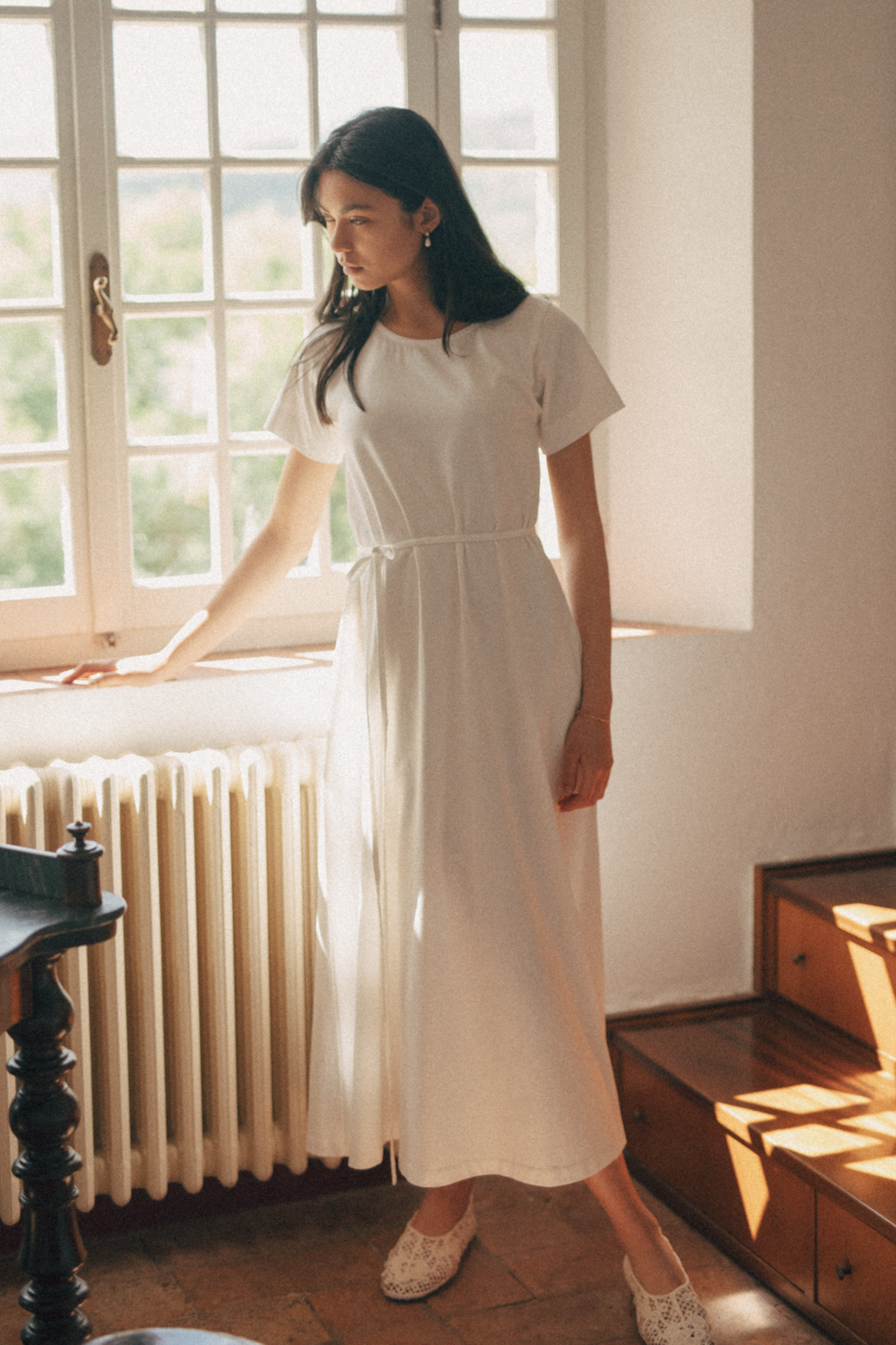 Model wearing the Palmer Dress in Salt by Gillian Stevens, full-length front view by a sunlit window