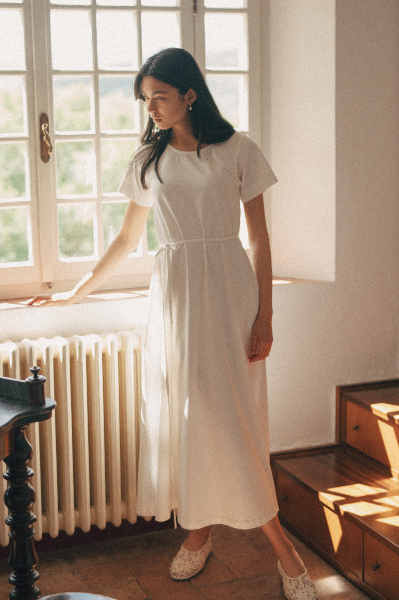 Model wearing the Palmer Dress in Salt by Gillian Stevens, full-length front view by a sunlit window